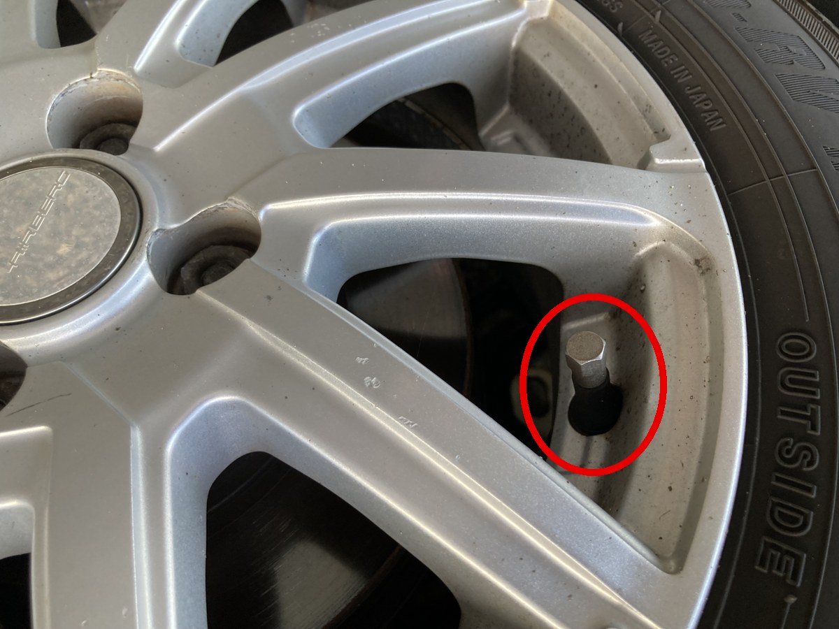 タイヤのホイールに付いたチューブレスバルブを赤丸で示した写真